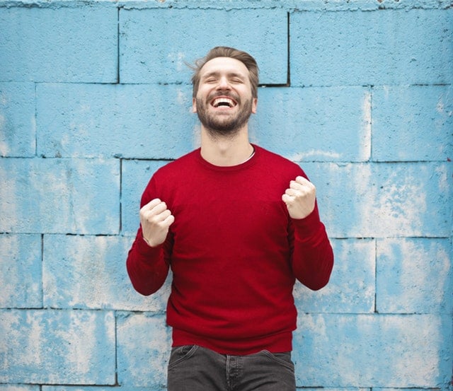 happy man standing in front of a wall