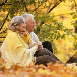 older couple sitting in a park in the fall