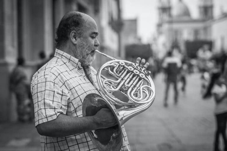 Black and white photo of man playing a French horn