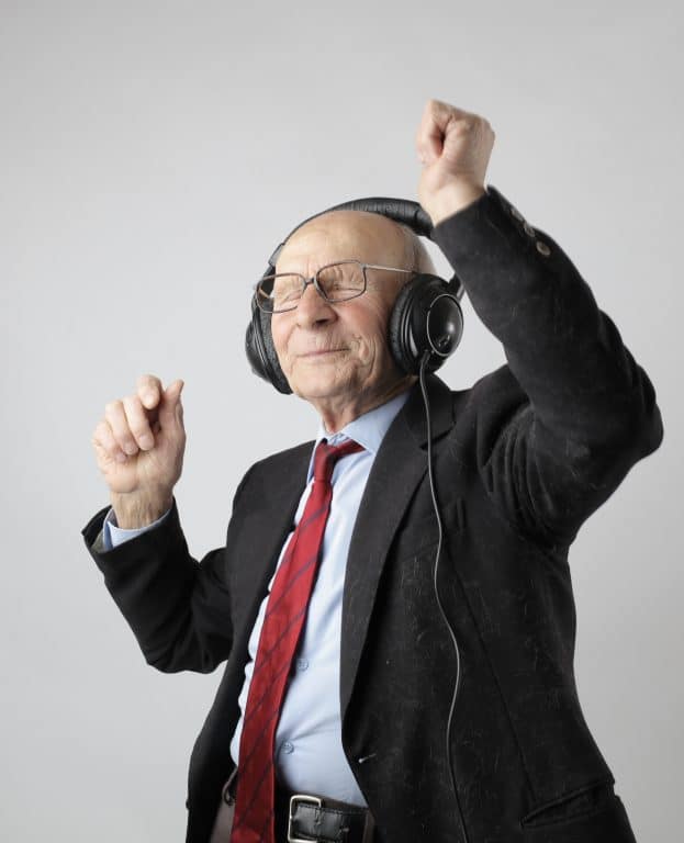 Older man listening to music through headphones and dancing 