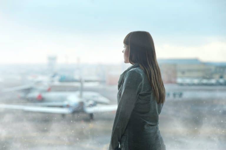 Woman looking out airport window as she waits for flight to board.