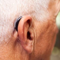 Close up of man wearing a behind-the-ear hearing aid.