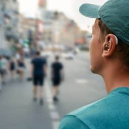 Young man with a hearing aid walking around a noisy city.