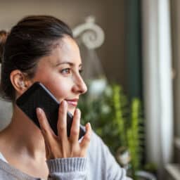 Young Adult Woman wearing hearing aids on phone.