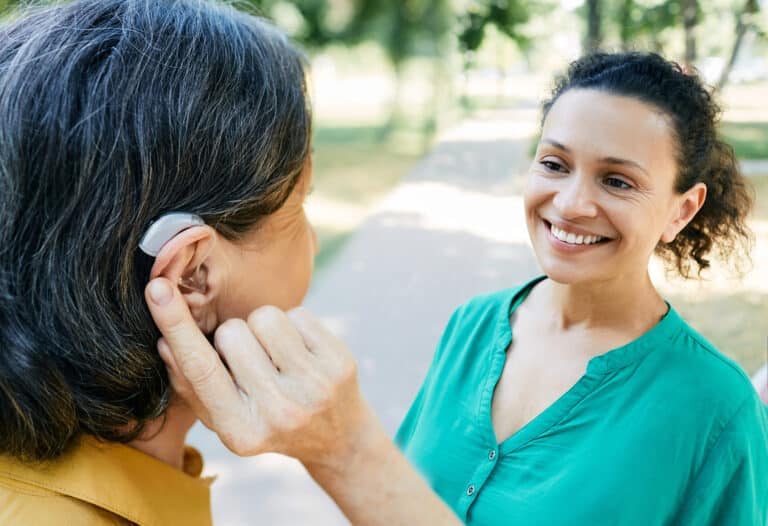 Woman with a hearing aid talking with her friend outside.