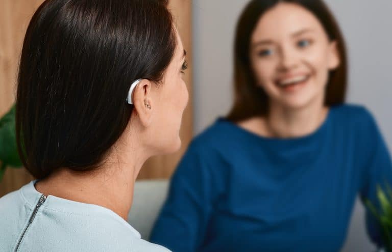 Young woman with a hearing aid chatting with her friend.