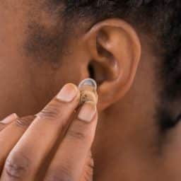 Close-up Of Female Hand Putting Hearing Aid In Ear