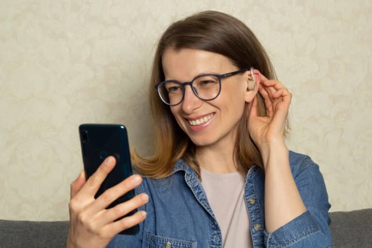 Woman holding her phone, showing off her new hearing aid